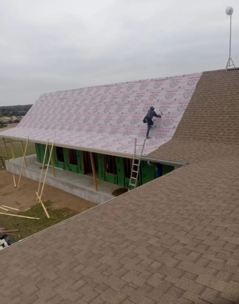 Worker preparing underlayment for a metal roof installation in Schertz